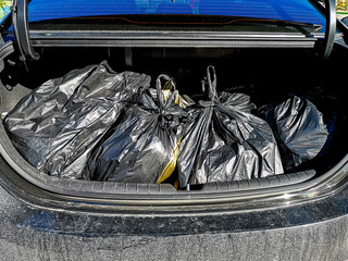 Garbage bags in the trunk of a car..Black plastic garbage bags in the hood of a car.