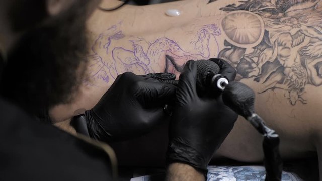 Professional tattoo artist showing the process of doing tattoo on back