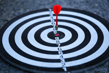 Fototapeta na wymiar Close up red dart arrow hitting target center dartboard background. Business targeting and focus concept