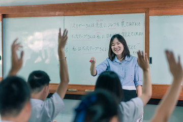 An Asian female teacher is teaching Japanese. The meaning of texts are 