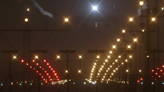 Jet airliner landing at night foggy weather with runway lights