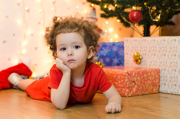 upset little girl waiting for a surprise. no christmas gifts for baby. A pensive little girl is waiting for Santa Claus and the promised gift.