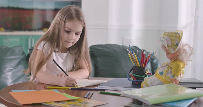Portrait of focused Caucasian girl drawing with her tongue out. Schoolgirl resting at home or doing homework. Hobby, education, studying concept. Cinema 4k ProRes HQ.