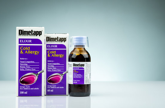CHONBURI, THAILAND-OCTOBER 14, 2018 : Dimetapp Elixir in amber bottle with measuring cup and packaging isolated on gradient background. Nasal decongestant and antihistamine drug. Medicine for cold.