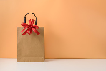 Mockup of blank craft package or Brown paper shopping bag with Red ribbon bow and handles. concepts New Year's gift or Christmas
