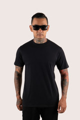 Man with tattoo wearing black t-shirt isolated on plain background