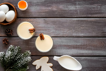 Ingredients for New Year drink eggnog - milk, eggs, cinnamon on dark wooden background top view frame copy space