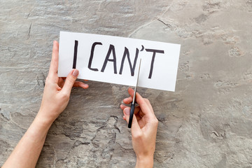 Motivation to be confident. Hands cut text I can't with scissors on grey background
