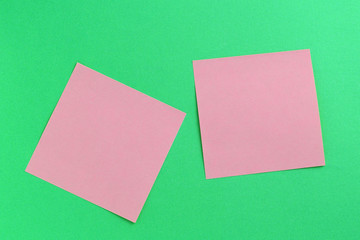 Empty pink sticker notes on a green background. Business concept, horizontal mock-up
