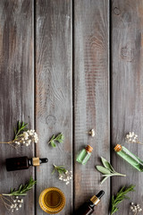 Essential oils and fresh herbs on dark wooden background top view pattern frame copy space