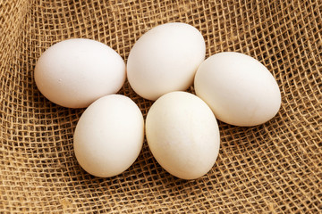 Chicken eggs lie on a background of burlap. View from above.