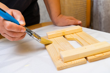 Girl varnishes a wooden detail.