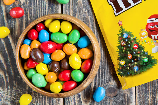 M&M's chocolate candy in a bowl and christmas bag on wooden background. Moscow - October 19, 2019