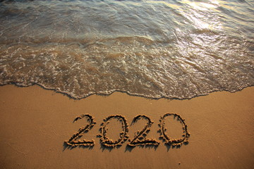 Happy New Year 2020 is coming concept on the sunset and tropical ocean beach lettering. 
