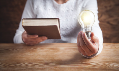 Girl holding light bulb and book. Knowledge, Creative, Wisdom