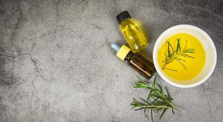 Essential oil bottle natural spa ingredients rosemary oil for aromatherapy and rosemary leaf on gray background - Organic cosmetics with extracts of herbs , top view