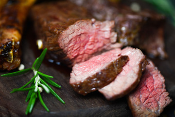 Roasted beef steak fillet with herb and spices served on wooden board - grilled beef meat slice medium rare steak ribeye