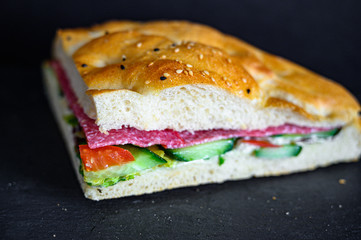 Flatbread sandwich with salami tomato cucumber salad and gravy