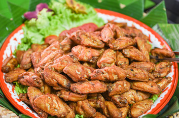 Fried chicken wings on plate - Baked chicken wings BBQ and vegetables on banana leaf background