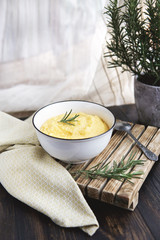 Italian traditional corn polenta  with butter. Served in white shallow dish on rustic wooden table...