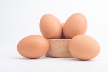 Organic fresh chicken eggs in a brown wooden bowl on a white background