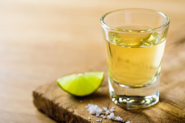 Tequila in a shot glass on a brown wooden background prepared for a party