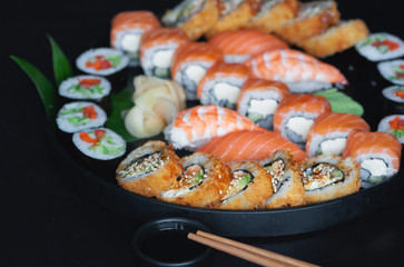  Various classic sushi and rolls from fresh ingredients over black background. Japanese cuisine.