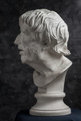 Gypsum copy of ancient statue Seneca head on dark textured background. Plaster sculpture man face.