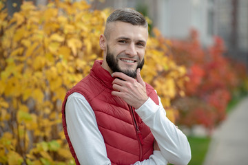 Joyful handsome young man touching his beard