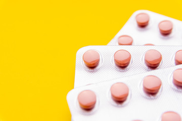 Pink pills on a yellow background. Place for text. From above