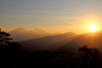 evocative image of sunset with silhouette of mountains in the background  and tree in the foreground