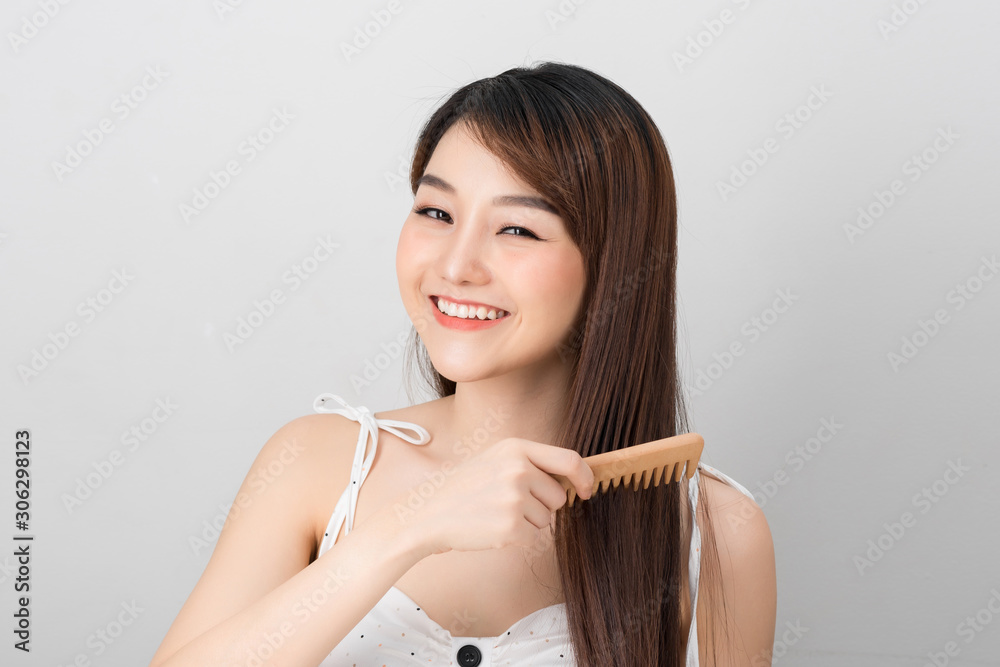 Wall mural beautiful girl combs her hair asian appearance