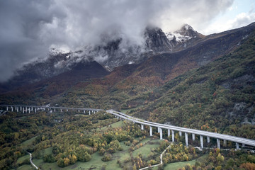 High autumn alpine speed road in Italia. Aerial view from above with clouds on the background