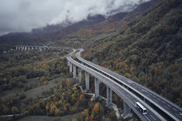 High autumn alpine speed road in Italia. Aerial view from above with clouds on the background