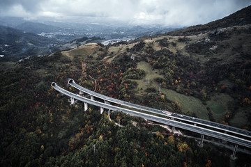 High autumn alpine speed road in Italia with exit or enter into the tunnel. Aerial view from above.