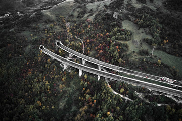 High autumn alpine speed road in Italia with exit or enter into the tunnel. Aerial view from above.