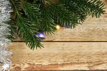 New Year's composition, Christmas decorations. Color Christmas balls lie on fir branches next to silver Christmas tinsel on a wooden background with copy-space