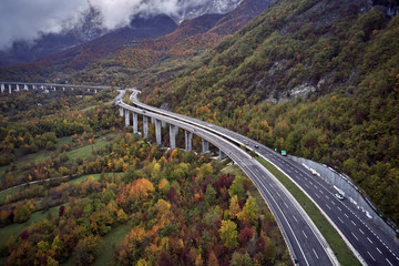 High autumn alpine speed road in Italia. Aerial view from above with clouds on the background