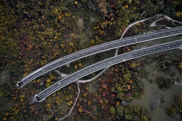 High autumn alpine speed road in Italia with exit or enter into the tunnel. Aerial view from above.