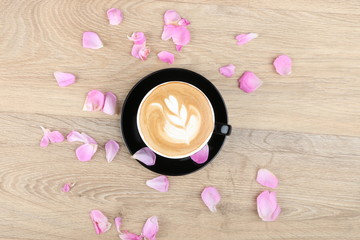 Coffee Cup and beautiful roses flowers - latte art foam  - Coffee in a black cup isolated on a wooden background - Cappuccino Latte Espresso Macchiato  