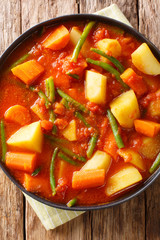 Ethiopian Yataklete kilkil healthy combination of potatoes, green beans and carrots closeup on a plate. Vertical top view