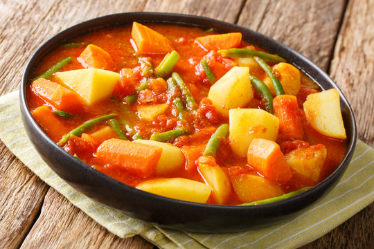 Vegetarian stew of carrots, green beans and potatoes in a spicy tomato sauce close-up in a bowl. horizontal