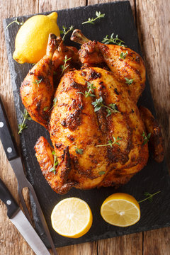 Freshly cooked rotisserie chicken with ginger and spices close-up on a slate board. Vertical top view