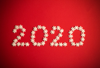 New Year 2020. Creative number 2020 written in white snowflakes on a red background for design. New Year 2020 concept