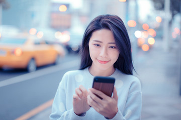 young Woman looking at smart phone in the city at night