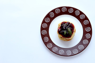 Cheesecakes stacked on top of each other, watered with blueberry jam, decorated with Basil leaves on a plate with a pattern on a white backgro