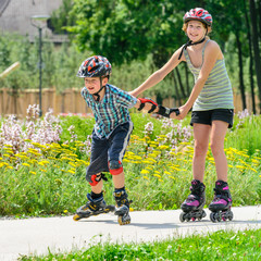Kinder haben Spaß auf Inline Skates im sommerlichen Park - obrazy, fototapety, plakaty