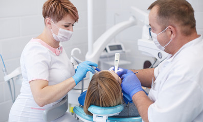 Fototapeta premium Doctor dentist treats teeth of a beautiful young girl patient.