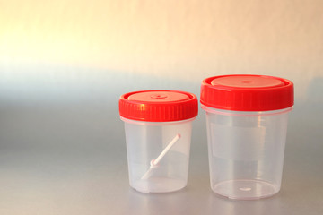 Jars for the collection of analyzes: feces and urine on a gray background. Selective focus. Prophylactic medical examination