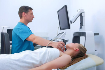 Doctor makes ultrasound scanning diagnostic of thyroid gland to woman in clinic, side view. Man doctor examination on ultrasonic scanner and preventive survey in hospital on modern equipment.